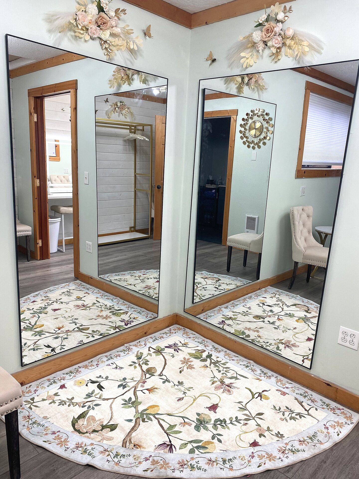 Corner full-length black-framed mirrors with floral rug and flower arrangements in the Sandy River Airport Bride's Room