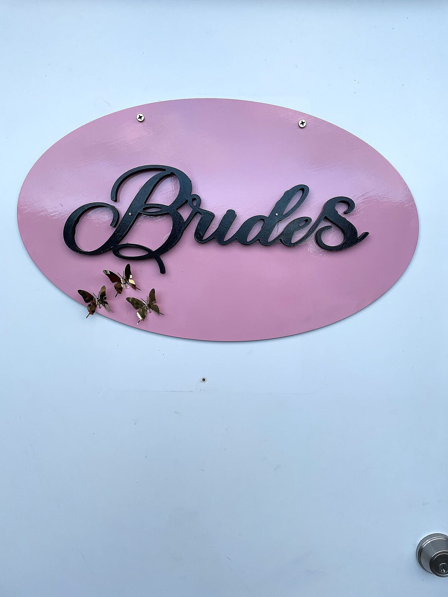 Pink oval Brides door sign with gold butterfly accents at Sandy River Airport wedding venue Oregon