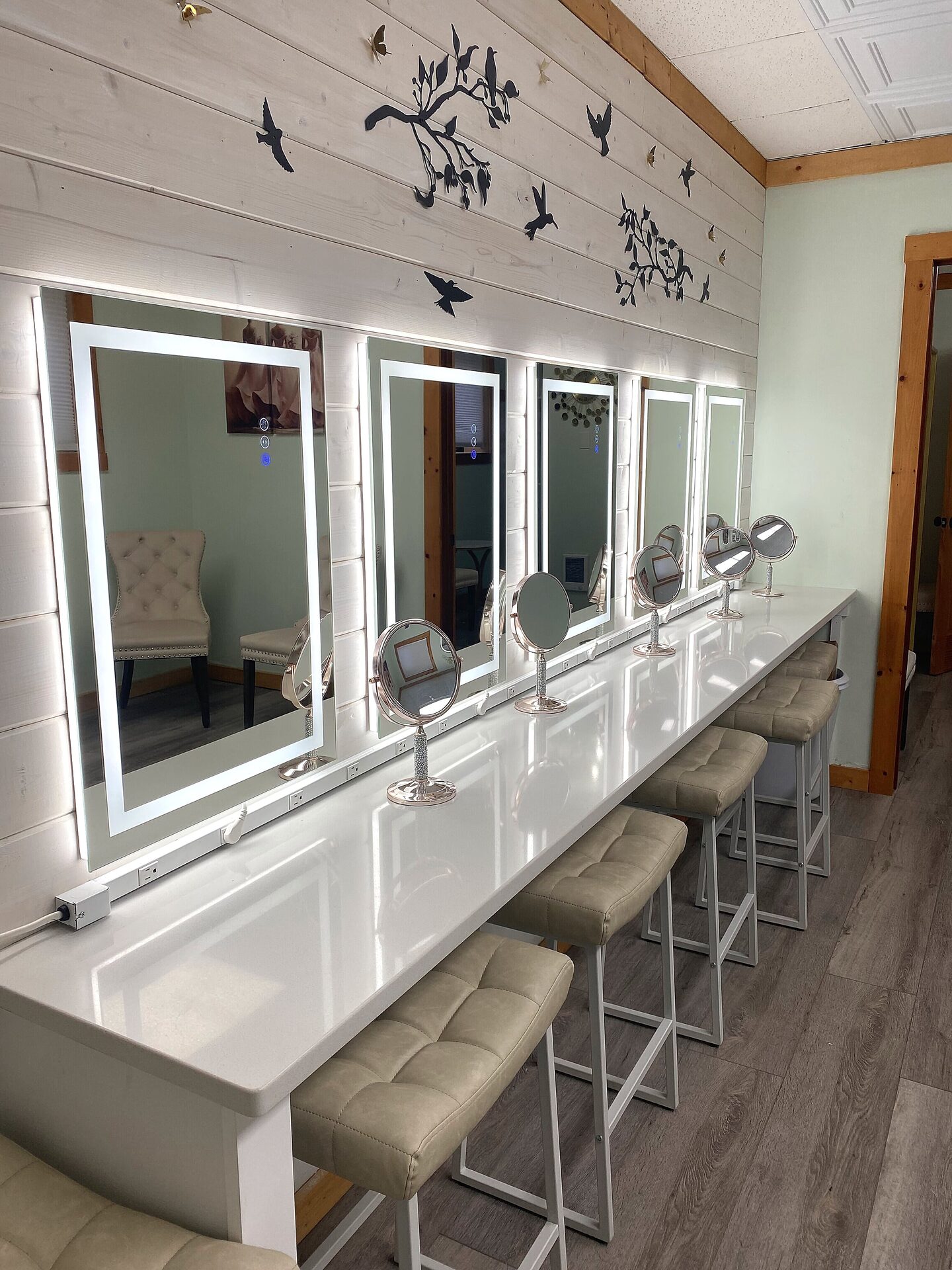 Five-station LED vanity counter with round rose gold makeup mirrors and gray stools in the Sandy River Airport Bride's Room