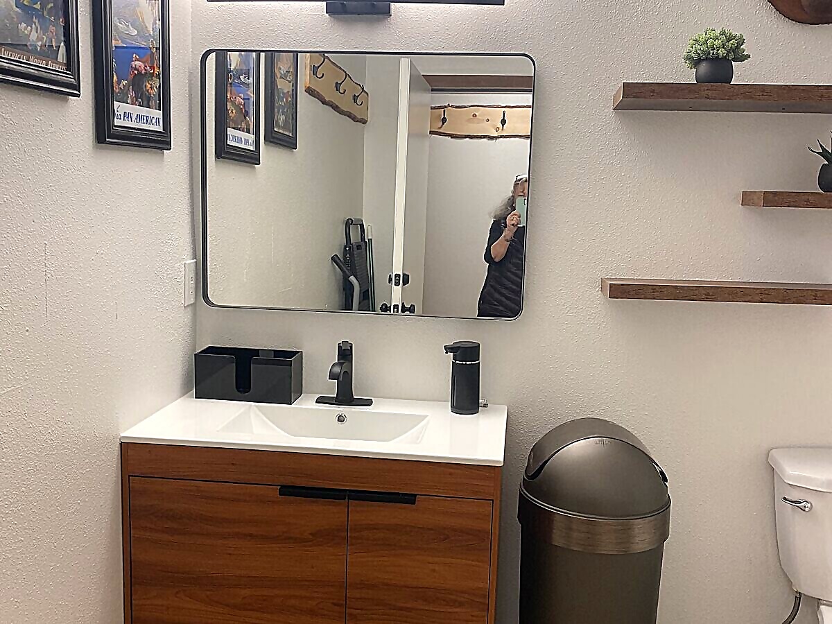 Groom's private bathroom with wood vanity, aviation blueprint art, and penny tile floor at Sandy River Airport