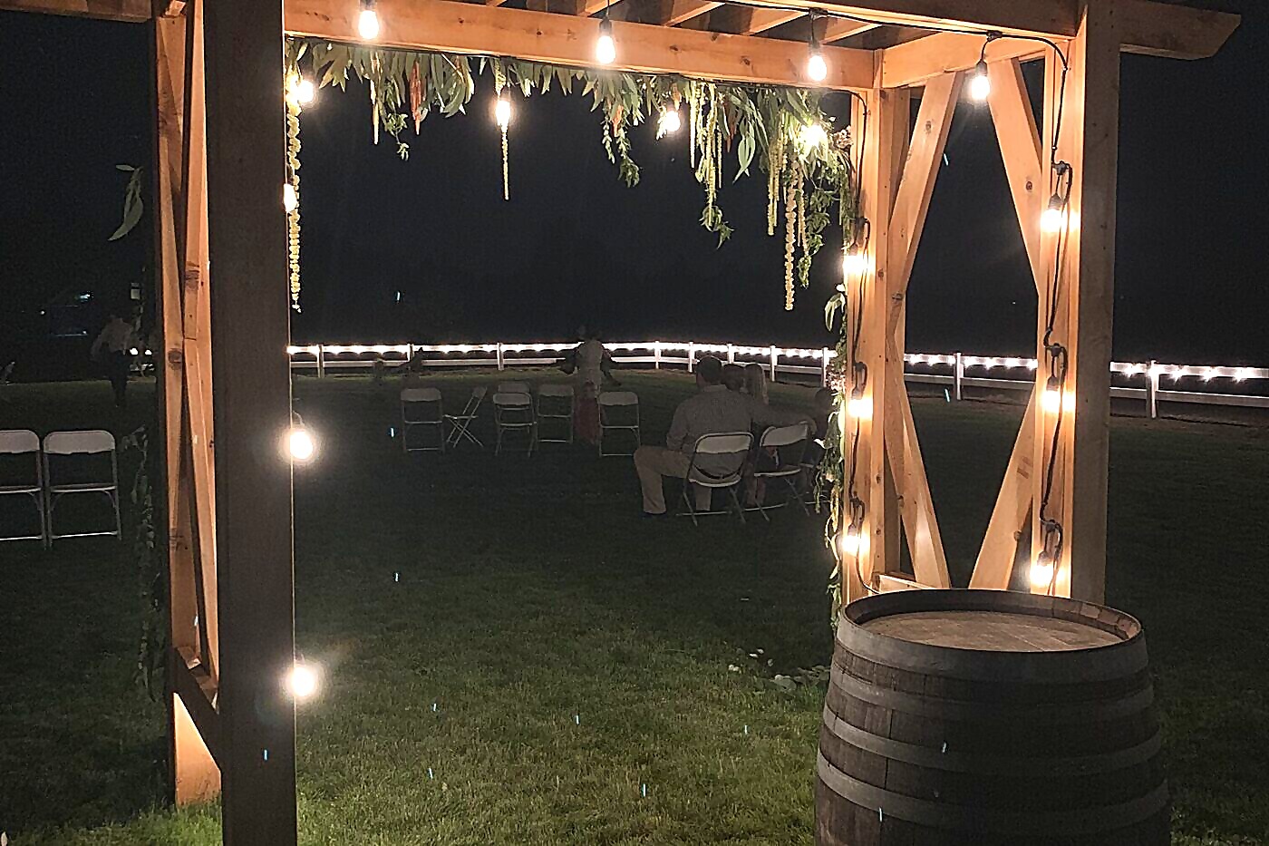 Rustic wooden arbor with string lights at night at Sandy River Airport wedding venue