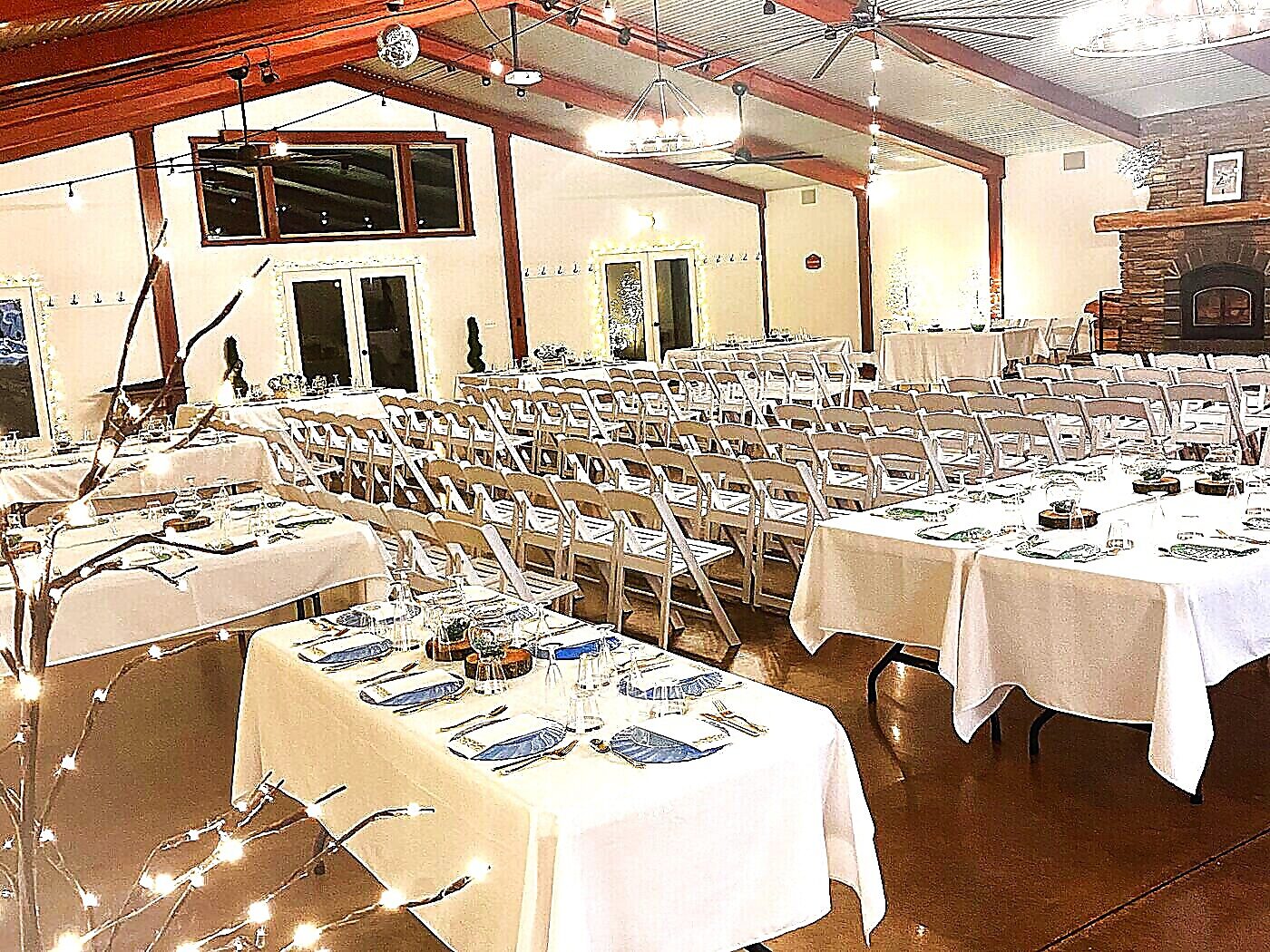 Indoor reception hall with twinkle lights, white tables, and vaulted ceiling at Sandy River Airport wedding venue Oregon